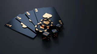 A hand of five playing cards with four aces, poker chips, and dice on a dark surface